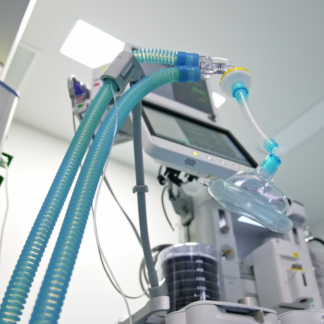 Modern surgery room with advanced equipment. Oxygen mask with blue tubes hanging near apparatus for lung ventilation. Low angle view