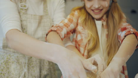 close up of the happy mother and daughter kneading a daugh with eggs together in the big glass bowl in the kitchen. portrait. indoor