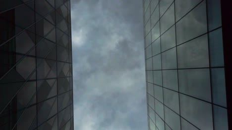 abstract shot of modern glass buildings looking up at cloudy sky cityscape