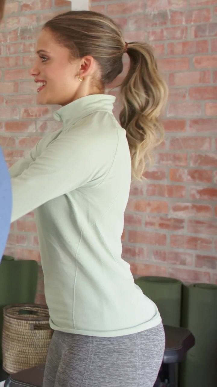 Video verticale: Iniziando una serie, donna in pullover e leggings che fa squat per il fitness in palestra con i tappetini.