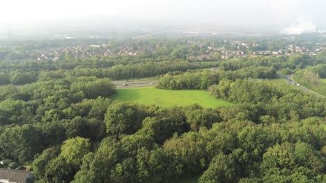 Urban-golden-hour-aerial-view-across-lush-foliage-urban-hazy-UK-scene-park-at-sunrise-pan-right