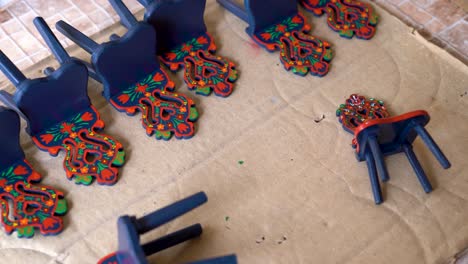painted wooden chair parts with intricate matyó floral motifs on workshop table