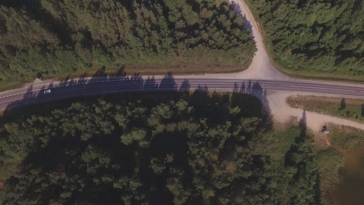 A White Car Turns From A Rural Gravel Road To A Main Asphalt Regional Road. Aerial Top-Down Active-Track Left