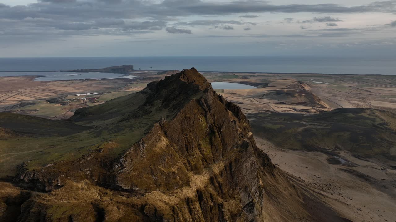 아이슬란드의 부르펠 (búrfell) 에 있는 은 산꼭대기에서 구름이 가득한 하늘 아래 해안 평야, 호수, 바다를 볼 수 있는 드론 사진