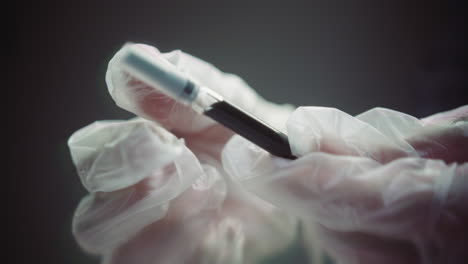 gloved hands prepare the syringe for injection