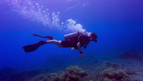 close up of scuba diver diving close to the bottom of the sea releasing bubbles