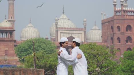 Dos-Amigos-Musulmanes-Saludándose-Y-Abrazándose-Mientras-Se-Reúnen-Para-Celebrar-El-Eid
