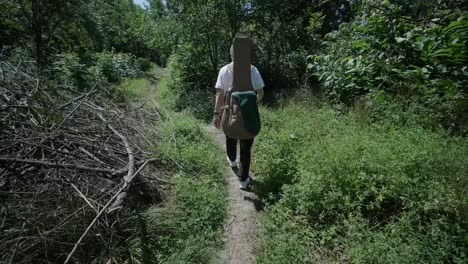 joven caminando con la guitarra en la calle cerca del bosque