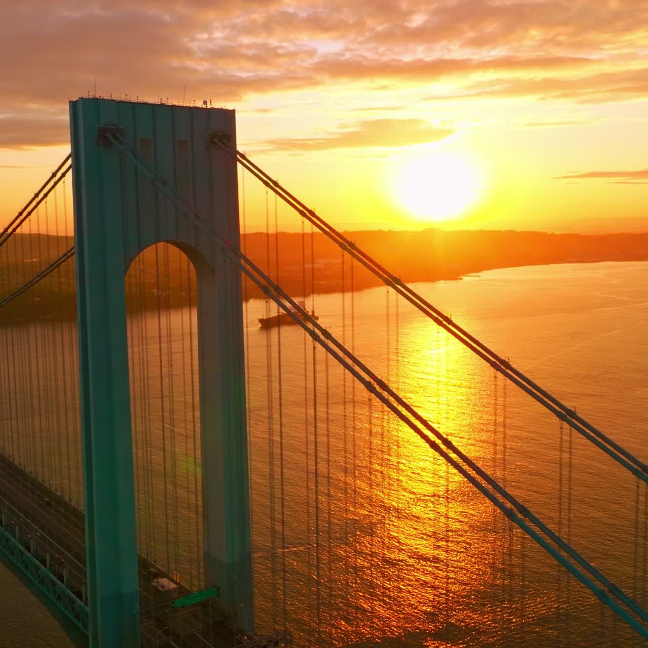 Bright huge sun reflecting in the East River. Beautiful Bronx-Whitestone bridge against sun setting over the city