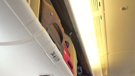 suitcase in a overhead baggage area in a airplane cabin ,