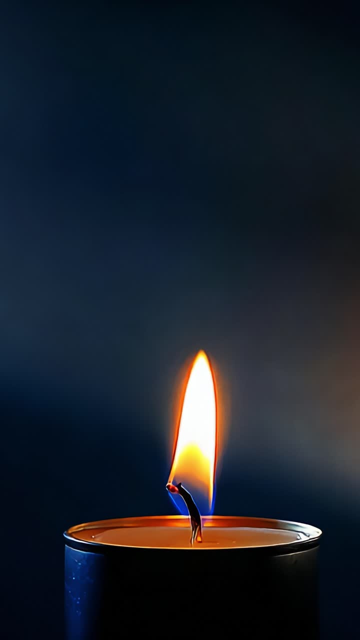 Un ipnotico primo piano di una fiamma di candela che tremola delicatamente, illuminando l'ambiente circostante con il suo bagliore caldo e creando un'atmosfera serena e rilassante nell'oscurità