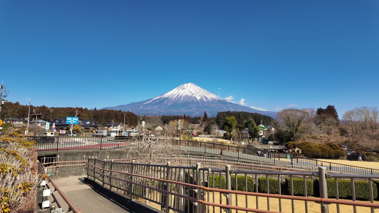 Una transizione cinematografica con rack focus che inizia su foglie gialle vivaci e bacche rosse, spostandosi su una vista nitida e ampia del Monte Fuji innevato sotto un cielo blu brillante