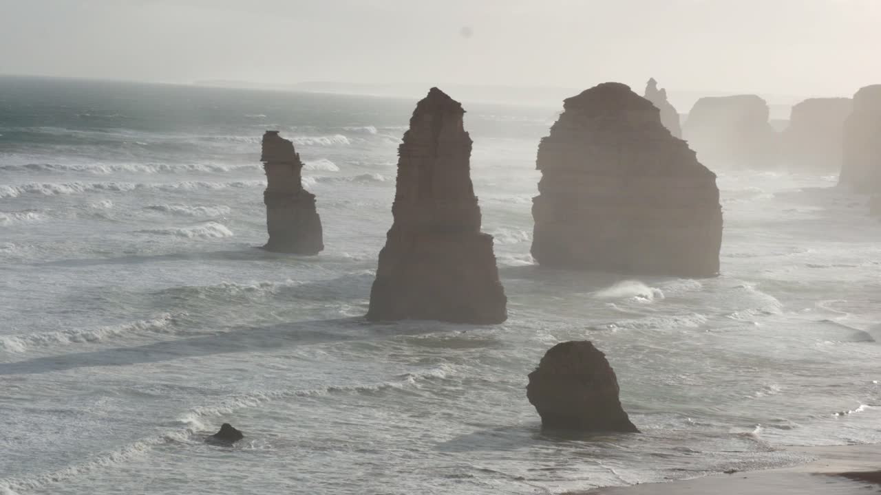 극적인 바다의 물결은 부드러운 아침 빛 아래 열두 사도들의 상징적인 석회암 어리에 부히고 있습니다.
