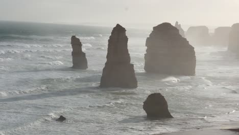 dramáticas olas del océano chocan contra las icónicas pilas de piedra caliza de los doce apóstoles bajo la suave luz de la mañana