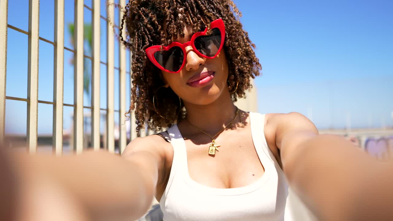 Woman taking a selfie with red heart sunglasses