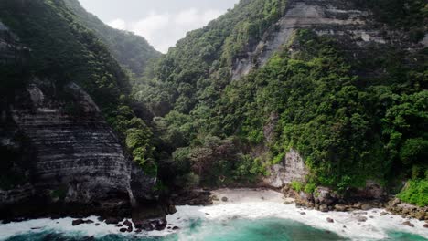 ocean waves splashing on rocky shore with limestone cliffs in nusa penida, bali, indonesia