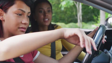 biracial sisters sitting in car and having driving lesson, in slow motion