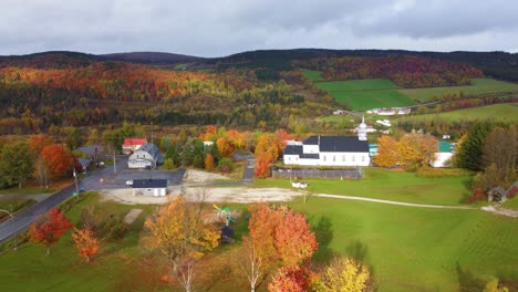 establishing drone shot of typical canadian town with autumn colors in region of estrie, quebec, canada