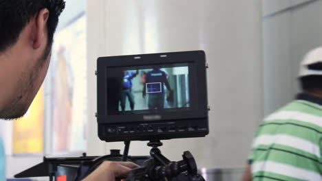 young man is setting his camera and monitor while the crew is preparing the set