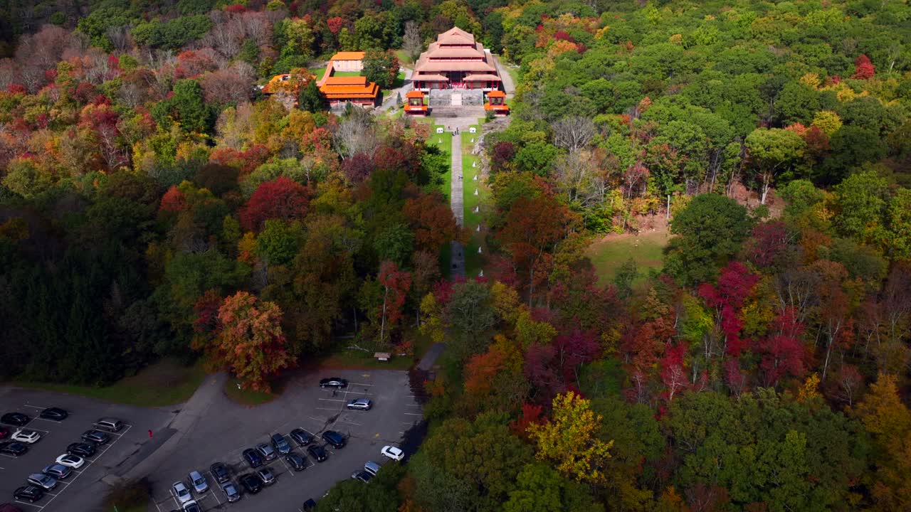 An aerial view over the Chuang Yen Monastery on a beautiful day, as the leaves of the surrounding trees begin to change for the autumn season