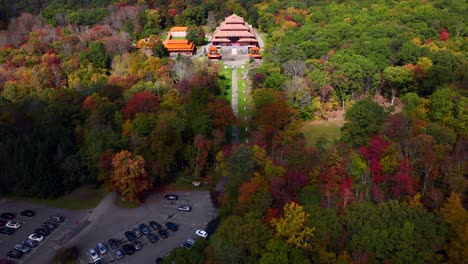 an aerial view over the chuang yen monastery on a beautiful day, as the leaves of the surrounding trees begin to change for the autumn season