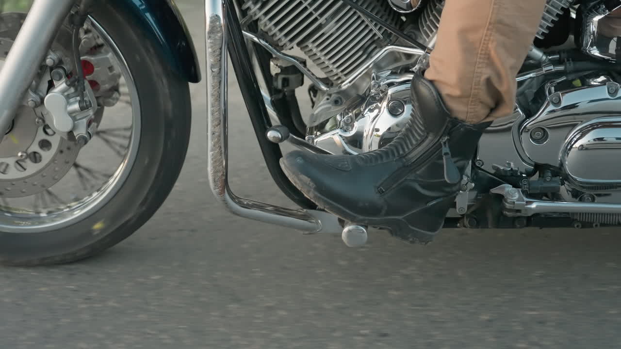 Close up of motorcycle front wheel spinning on asphalt road during travel, showing chrome rim, brake disc, and motion blur that highlights speed, dynamics, and energy