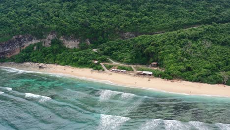 Kleines-Restaurant-Am-Leeren-Weißen-Sandstrand-Von-Nyang-Nyang-In-Uluwatu-Bali-Mit-Krachenden-Meereswellen,-Luftaufnahme