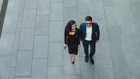 Top-view-couple-walking-together-at-sidewalk.-Business-partners-talking-outside