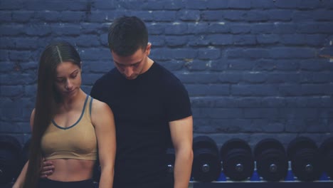 a beautiful young girl and her well-constructed boyfriend together show a gesture class. they are glad to see each other in the gym.