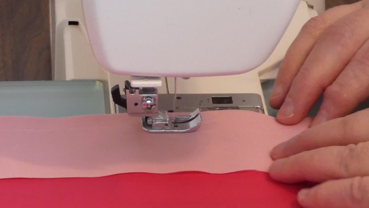 A woman sews a seam on a sewing machine.