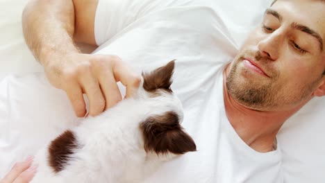 happy young man lying on bed stroking his puppy in the bedroom 4k 4k