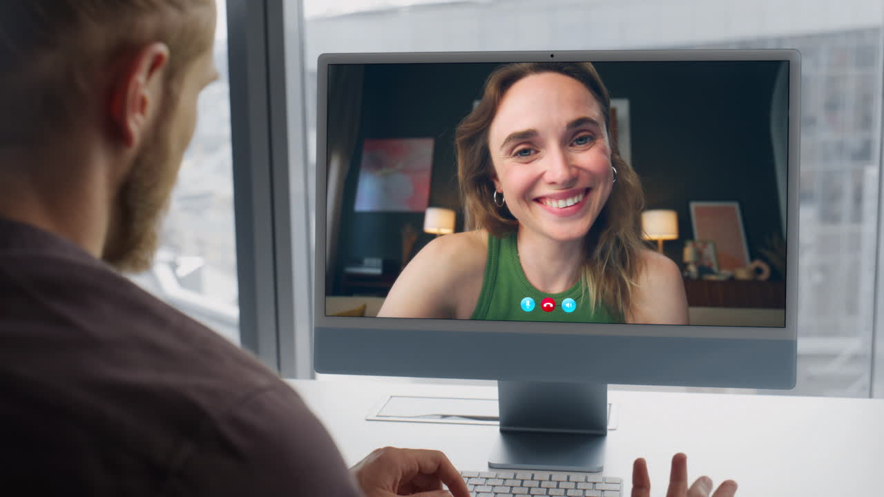 Office worker videocalling computer colleague at big windows workplace closeup