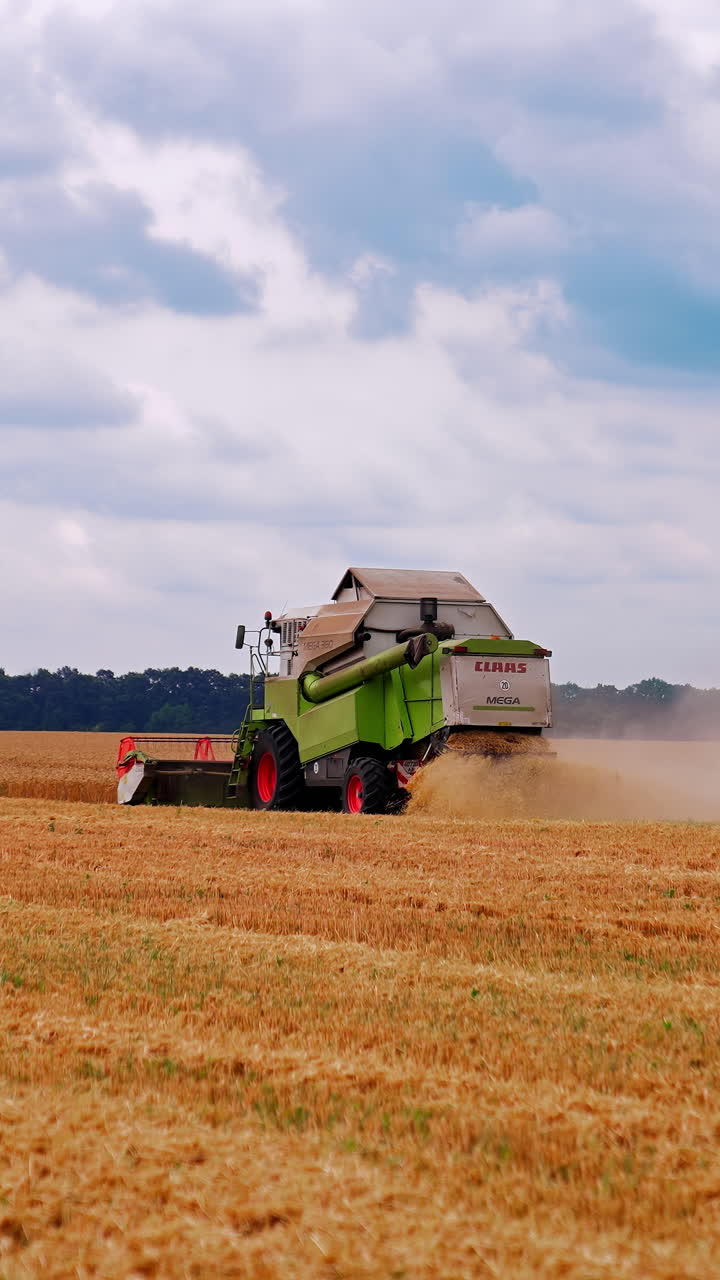 Kyiv, Ukraine, 2 May 2025: Combine harvester working on field. Harvesting machine driver cutting crop in farmland. Vertical video