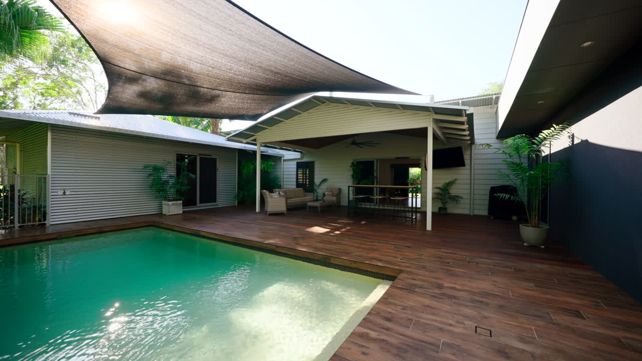 casa tropical rural piscina rectangular y patio sala de estar en una cubierta de madera sombreada por un dosel de lona