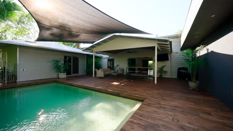 casa tropical rural piscina rectangular y patio sala de estar en una cubierta de madera sombreada por un dosel de lona