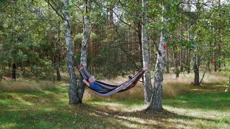 Hombre-Relajándose-En-Una-Hamaca-Entre-árboles-En-El-Bosque-De-Prądzonka-En-El-Norte-De-Polonia