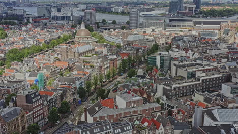 Amsterdam-Netherlands-Aerial-v8-birds-eye-view-overlooking-residential-buildings-along-nieuwezijds-voorburgwal-street,-tilt-up-reveals-major-railway-train-station-and-neighborhoods---August-2021