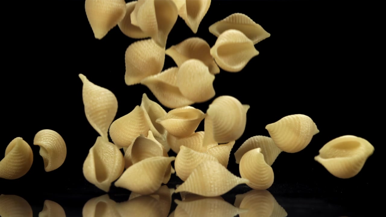 Rohe Conchiglie-Nudeln fallen in Zeitlupe