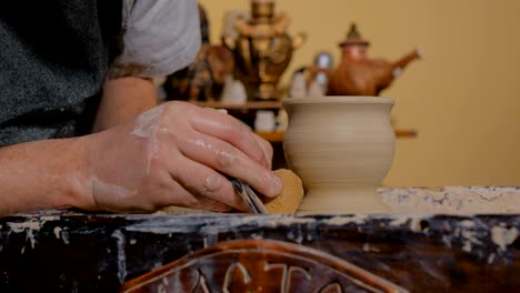 professional potter shaping mug with special tool in pottery workshop