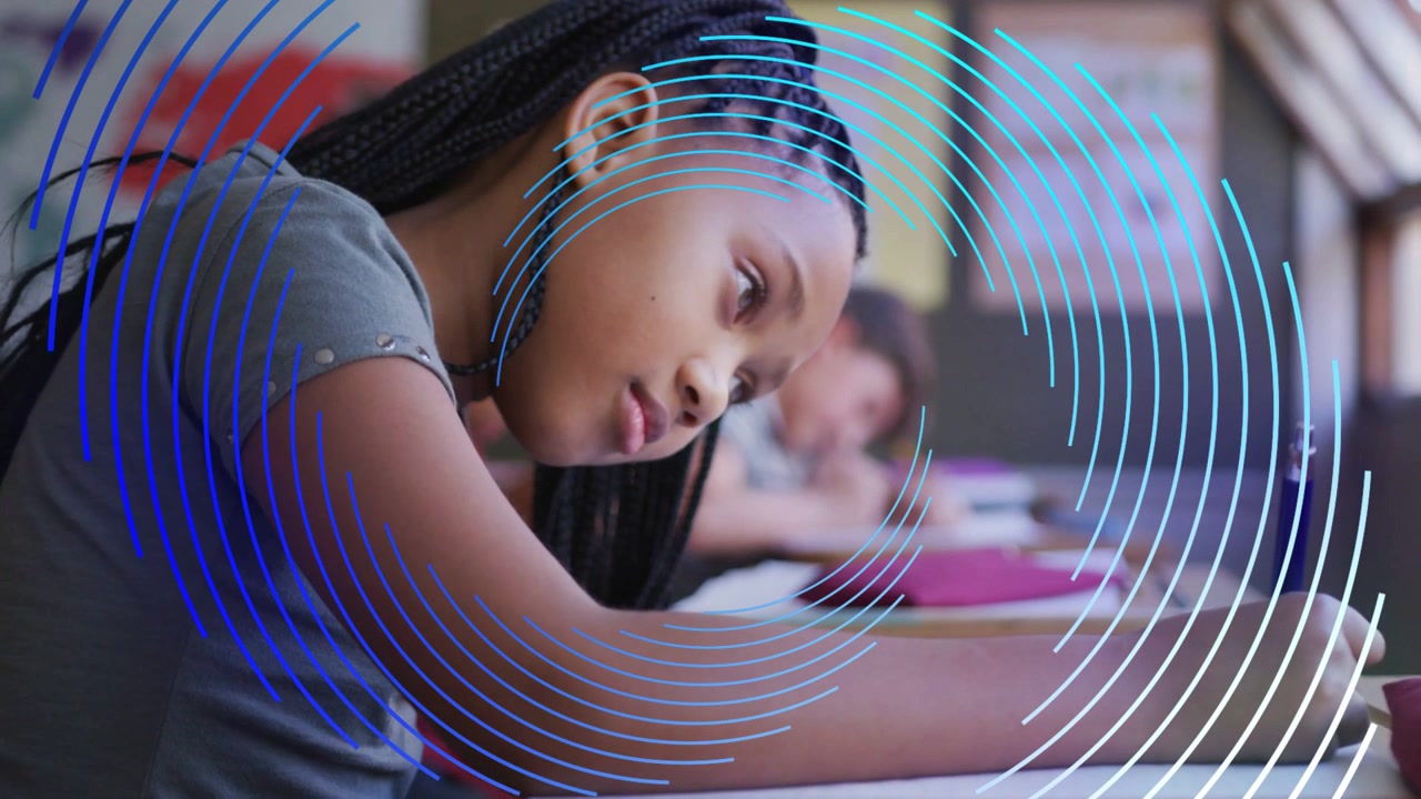 Female student after teacher prompt leaning over notebook, writing classwork, blue circles sweeping