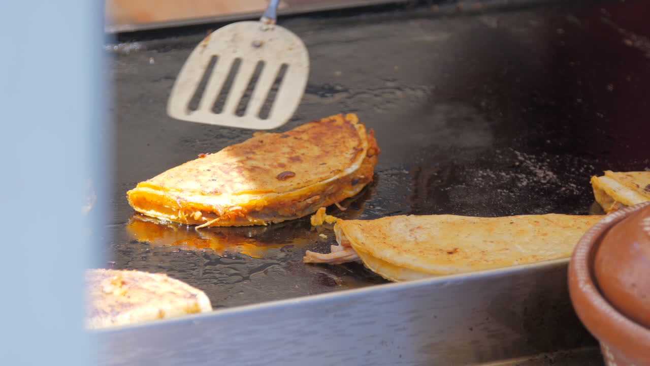Quesadilla messicana capovolta sulla griglia in una bancarella di street food di giorno.
