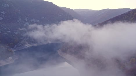 drohnenansicht von piva lake canyon montenegro, die durch wolken fliegt, luftaufnahme