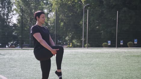 On a Sunny Day a Woman Does Dynamic Leg Stretches in a Field Boosting Her Flexibility. On a sunny day, a woman does dynamic leg stretches in a field, boosting her flexibility and fitness