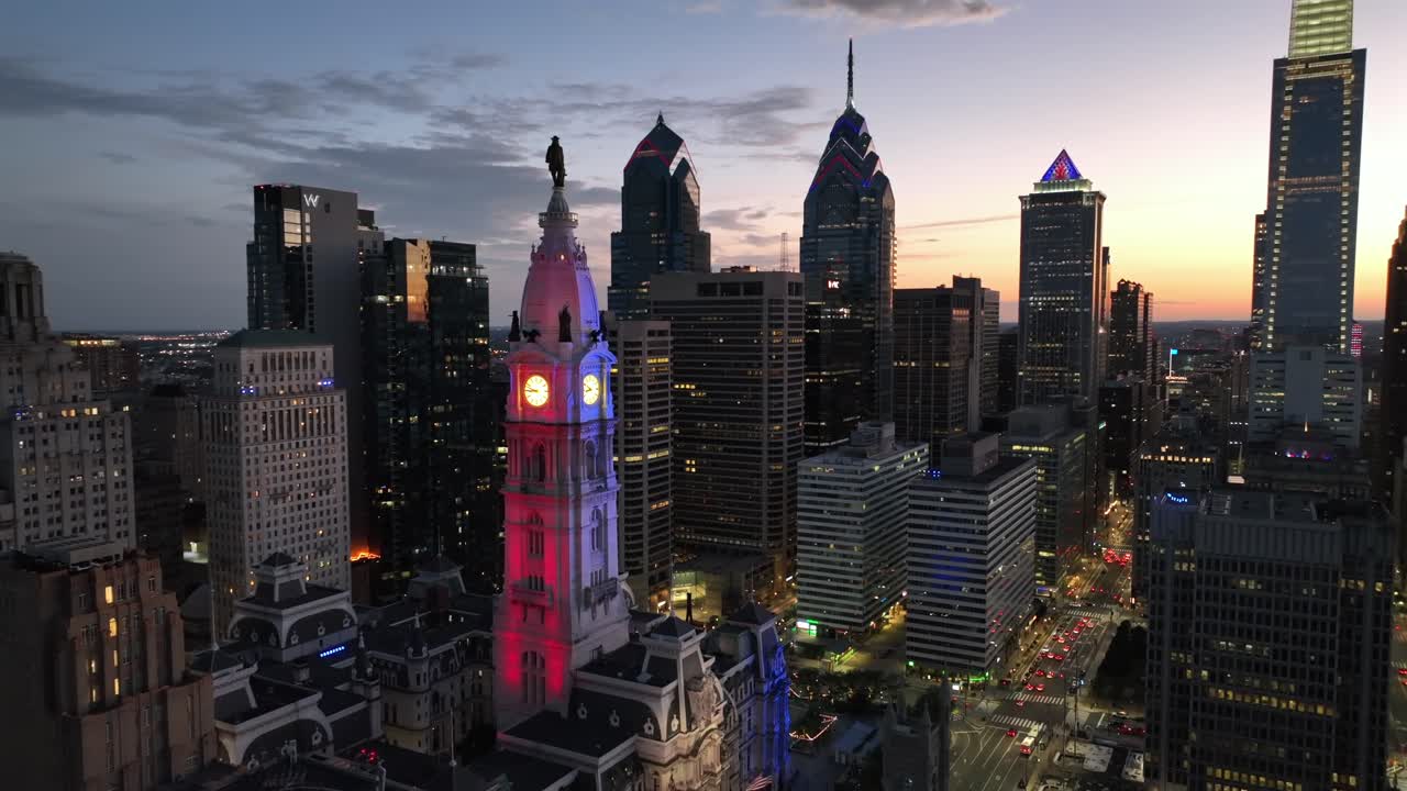 Establishing drone scene of American metropolis of Philadelphia after sunset. Rotating ventilator on rooftop of buildings. Famous city hall tower and skyscrapers of downtown. Aerial tilt up wide shot