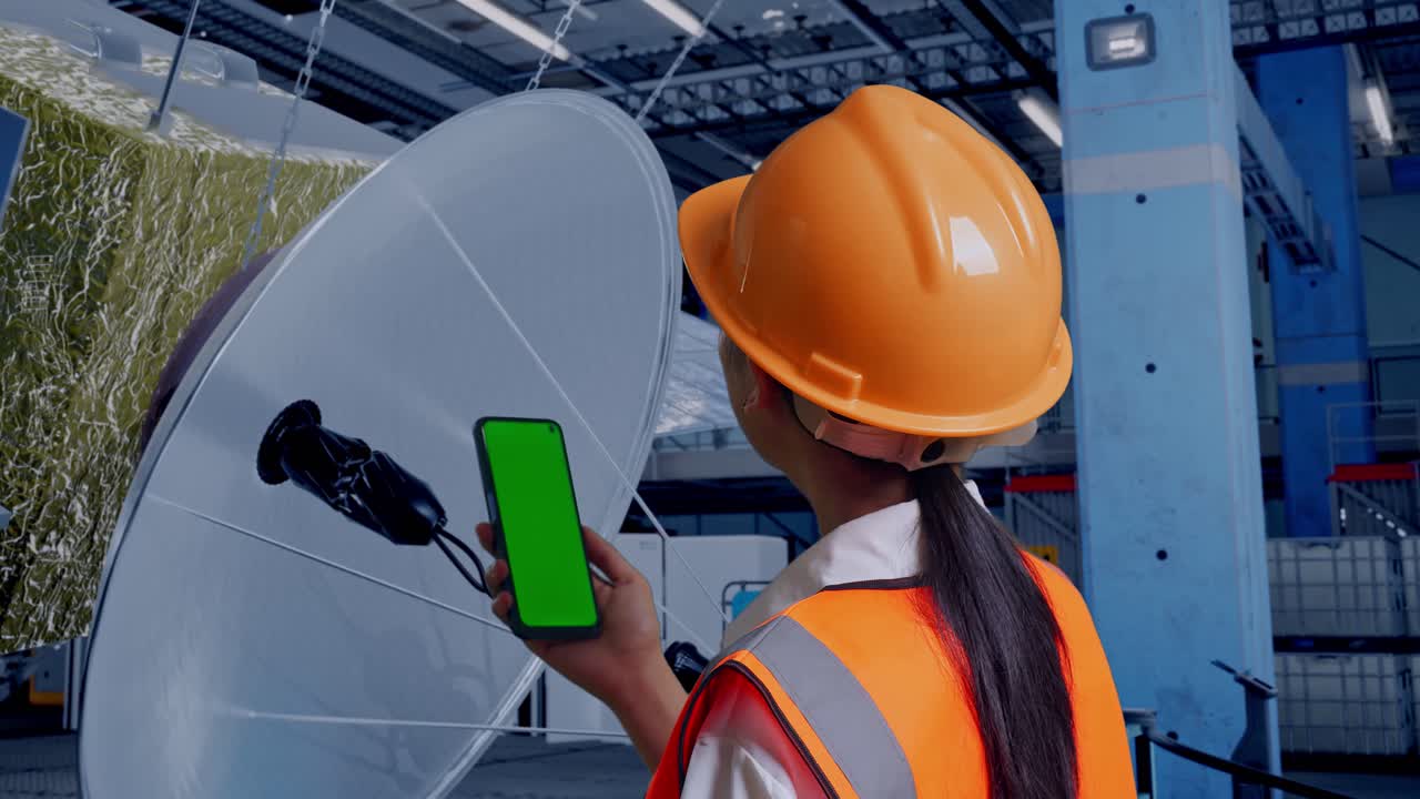 ingeniero usando un teléfono inteligente con pantalla verde frente a la antena parabólica