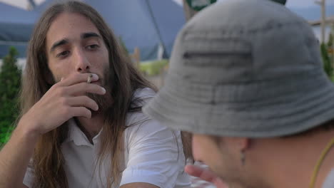 Men-friends-talking-and-smoking-in-outdoor-cafe