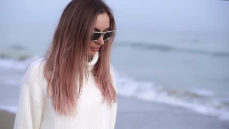 calm woman standing on the beach, sea waves reflected in the sunglasses