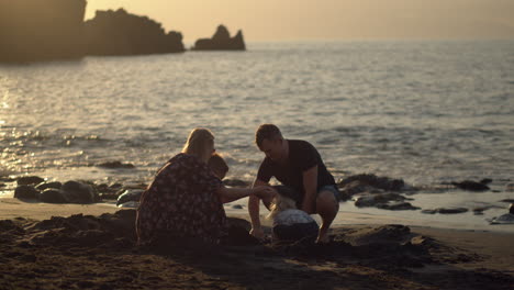 Family-of-four-playing-in-sand-on-the-evening-seashore