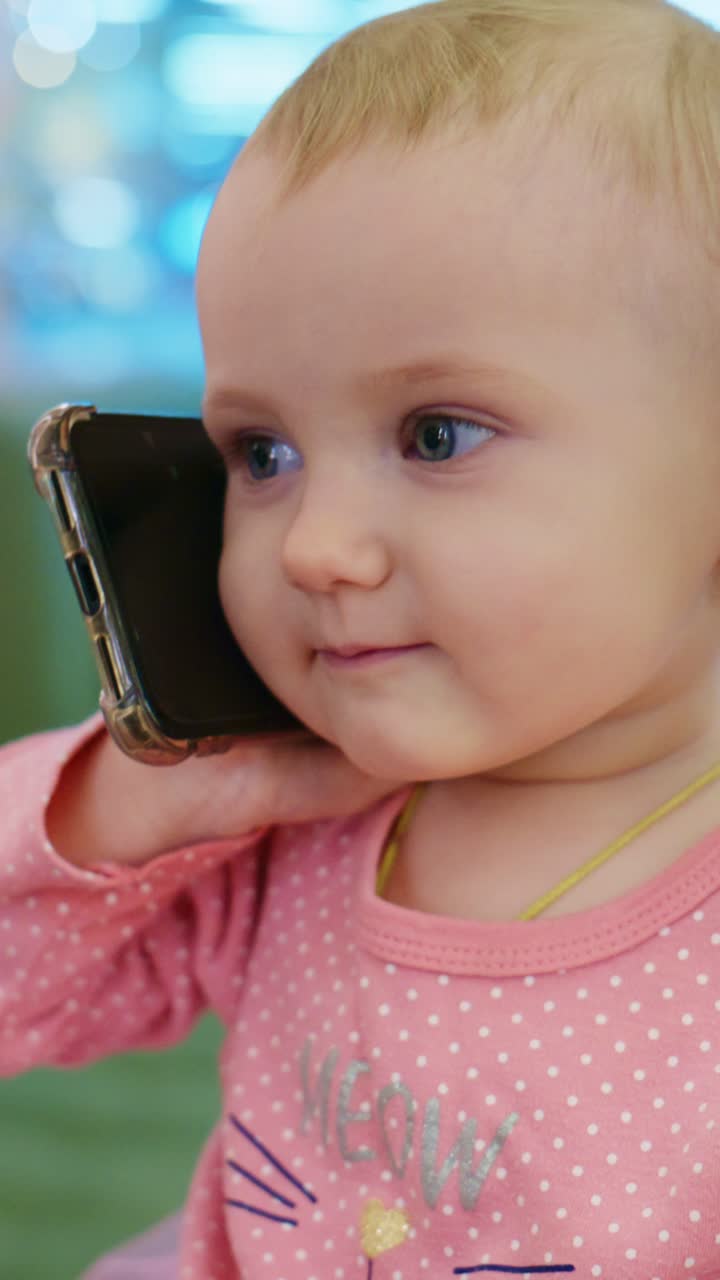 Un adorable niño pequeño interactúa jugando con un smartphone, mostrando alegría y curiosidad en un entorno luminoso y alegre