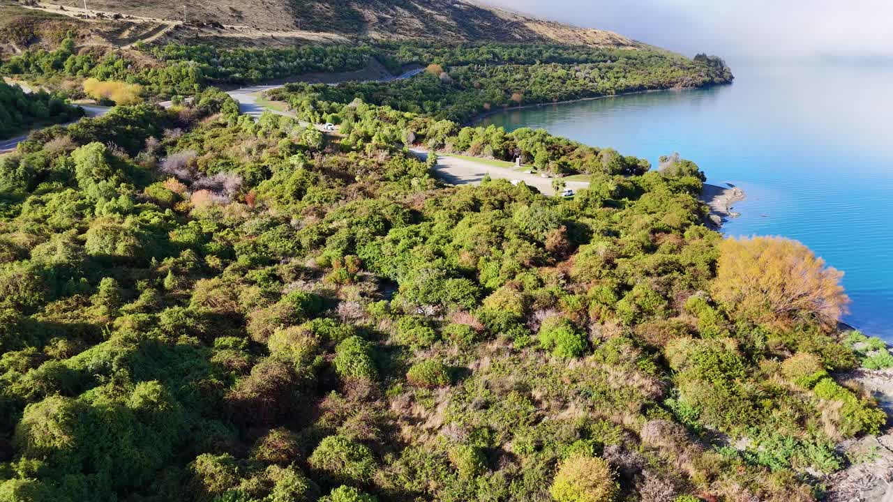 Drone footage captures a serene lake surrounded by lush autumn foliage, highlighting vibrant colors and tranquil waters